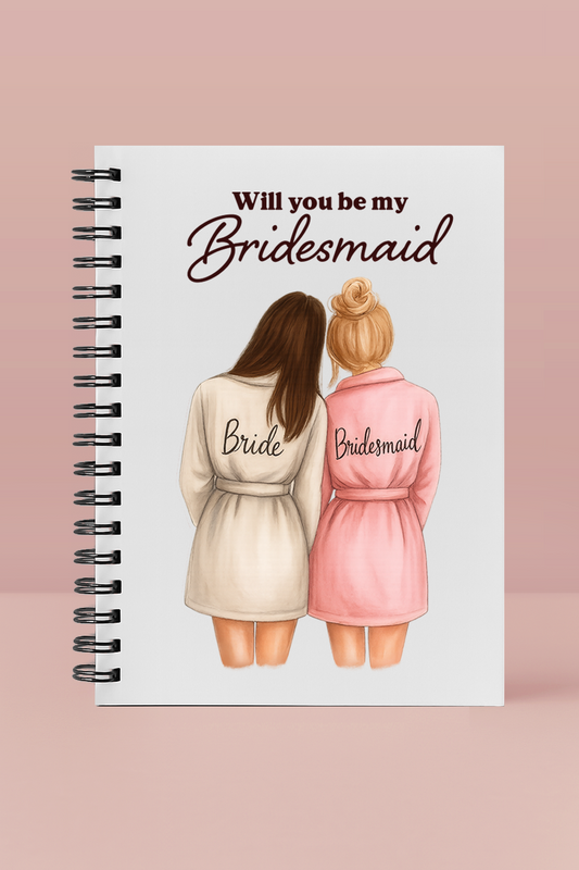 Notebook with illustration of two women in robes, one labeled 'Bride' and the other 'Bridesmaid', on a pink background.